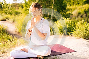 Attractive young woman is meditating and doing breathing exercising sitting in pose of lotus