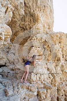 Attractive young woman in one-piece swimsuit among rocks