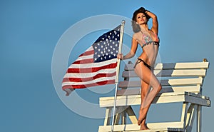 Attractive young woman with perfect slim fit body in bikini posing on the lifeguard tower.