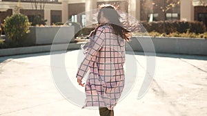 Attractive young woman playfully turns around at the camera. girl in autumn coat with back view. the girl is running