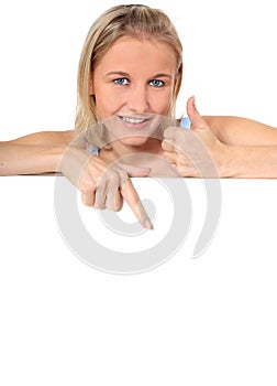 Attractive young woman points down blank sign