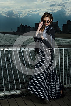 Attractive young woman posing on the pier, with effective clouds and lighting from coming thunderstorm.