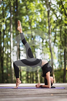 An attractive young woman practicing yoga, performs a leg-lifting exercise at Urdhwa Dhanurasana, a bridge pose