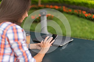 Attractive young woman reading a text message on her cell phone. Girl sitting outdoors using smartphone