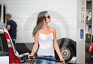 Attractive, young woman refueling her car in a gas station