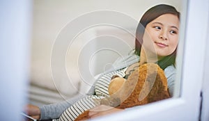 Shes already bought babys first teddy. an attractive young woman relaxing with a teddy bear on the sofa at home.