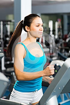 Attractive young woman runs on a treadmill