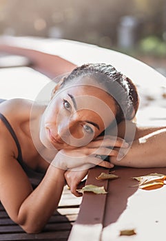 An attractive  young woman with a sad pensive expression in a park on a sunny day. Shallow depth of field female creative portrait