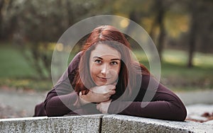 An attractive young woman with a sad pensive expression in a park on a sunny day. Shallow depth of field female creative portrait