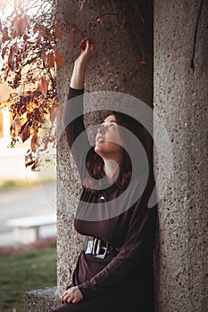 An attractive young woman with a sad pensive expression in a park on a sunny day. Shallow depth of field female creative portrait