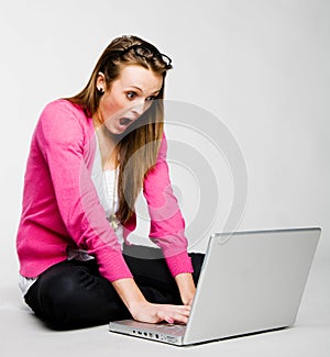 Attractive young woman shocked by her laptop