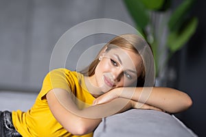 Attractive young woman sit sofa hold hand head good mood indoors inside apartment