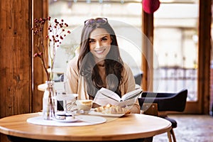 Attractive young woman sitting in the cafe and reading a book