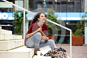 Attractive young woman sitting on steps with notebook and smiling