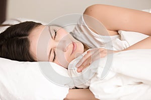 Attractive young woman sleeping comfortably in bed, close up hea