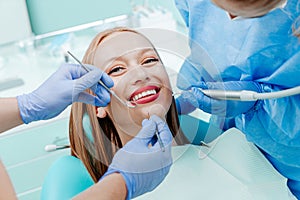 Attractive young woman smilling with natural white teeth in dental clinic. Hands doctor dentist with medical tools. Healthy teeth