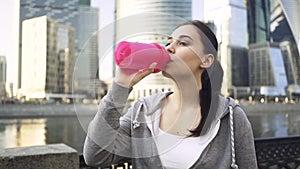 Attractive young woman in a sportswear drinking water in Moscow city