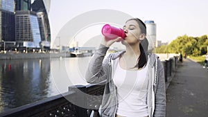 Attractive young woman in a sportswear drinking water and walking in Moscow city