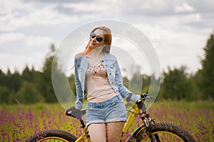 Attractive young woman in sportswear in a flower field with bike