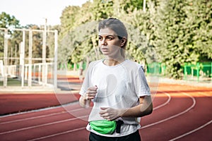 Attractive young woman in sportswear jogging at the stadium.