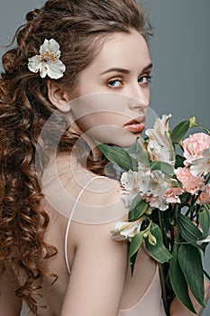 Attractive young woman with spring flowers bouquet on grey