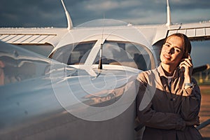 Attractive young woman standing near aircraft at airdrome