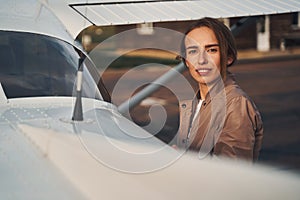 Attractive young woman standing near plane at airdrome