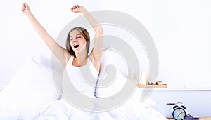 An attractive young woman stretching in bed after waking up