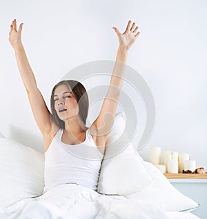 Attractive young woman stretching in bed after waking up