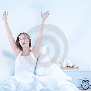 An attractive young woman stretching in bed after waking up