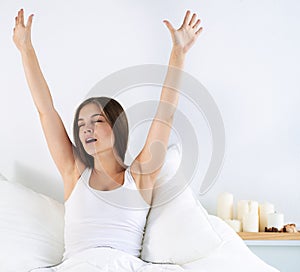 Attractive young woman stretching in bed after waking up