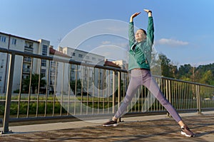 Attractive young woman stretching before her early morning run along the embankment of river.