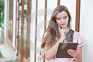 Attractive young woman student looking at pad browsing standing outdoors