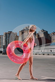 attractive young woman in stylish pink swimsuit with inflatable ring