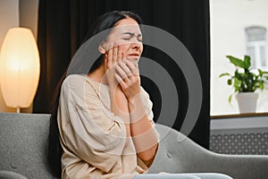 Attractive young woman suffering from toothache. Woman holding her cheek in pain.