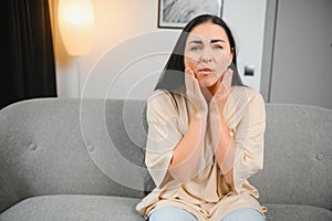 Attractive young woman suffering from toothache. Woman holding her cheek in pain.