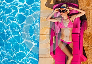 Attractive young woman sunbathing on chaise lounge