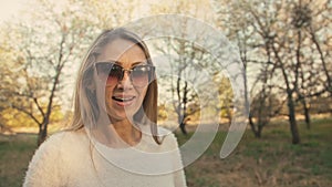 Attractive young woman in sweater, jeans is dance and spinning among blossom apple tree. Sunset, spring orchard and