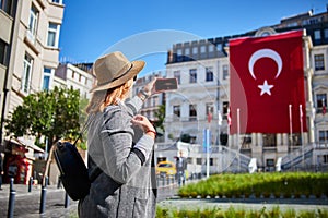 Attractive young woman taking pictures on background of Turkish flag on Beyoglu Municipality building in Istanbul