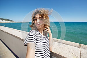 Attractive young woman taking selfie outside by the sea
