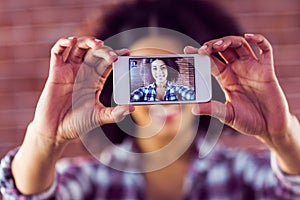 Attractive young woman taking selfies with smartphone