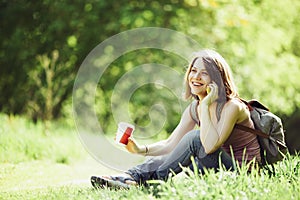 Attractive young woman talking by phone and holding cup of coffee