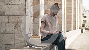 Attractive young woman texting outside in summer