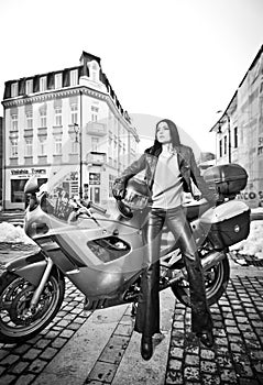 Attractive young woman in urban fashion shot near motorcycle. Beautiful fashionable young girl in black leather outfit