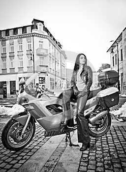 Attractive young woman in urban fashion shot near motorcycle. Beautiful fashionable young girl in black leather outfit