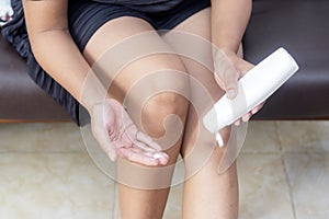 Attractive young woman using hand body lotion on her legs home beauty care