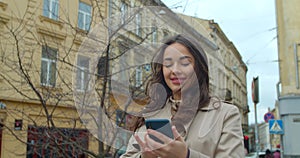 Attractive young woman using phone in the city center. Chatting with friends, girl using cellphone outdoors. slow motion