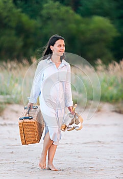 Attractive young woman walking on seacoast sand at sunset sunlight
