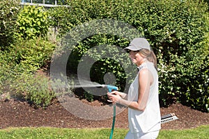 Attractive young woman watering the plants in the garden