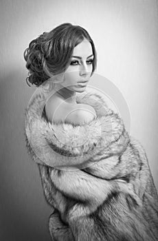 Attractive young woman wearing a fur coat posing provocatively indoor. Portrait of sensual female with creative haircut